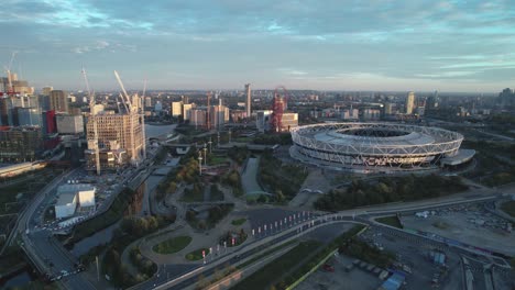 West-Ham-United-football-stadium-with-London-city-landmark-venue-aerial-view-pull-back-across-cityscape