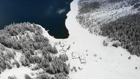 Luftaufnahme-Des-Oeschinensees-In-Kandersteg,-Schweiz-Mit-Schwenk-Von-Schneebedeckten-Bäumen-Zu-Berggipfeln-In-Reflexion,-Aber-In-Wolken-Verborgen