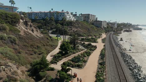 Aerial-view-over-two-ladies-walking-along-the-beach-path-near-San-Clemente,-California
