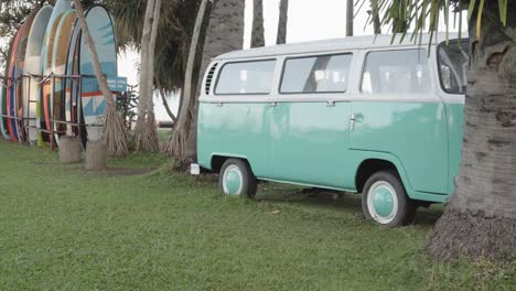 A-pan-reveal-shot-of-a-classic-VW-Bus-on-a-beach-with-surfboards,-a-perfect-setting-for-a-retro-hippy-carefree-lifestyle,-Pattaya,-Thailand