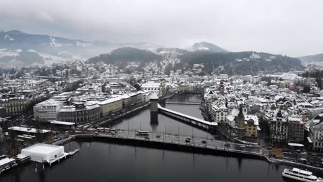 Aerial-view-of-Kappelbrücke-and-Lucerne,-Switzerland-as-the-city-is-covered-in-snow-in-winter