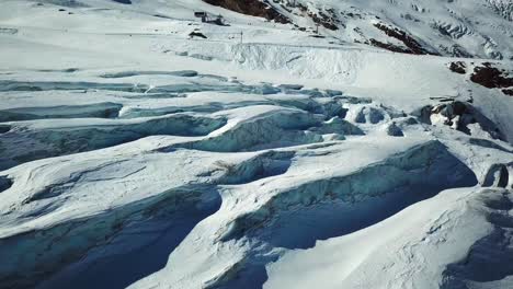 Glaciar-Azul-Con-Grietas-En-Los-Alpes-Suizos,-Pista-De-Esquí-En-El-Fondo