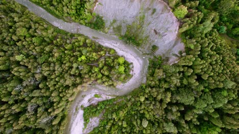 Narrow-winding-river-cutting-through-dense-forest-woodland-with-rocky-erosion