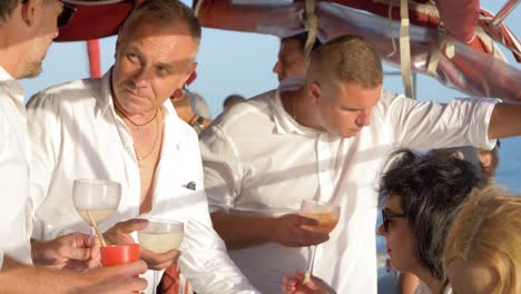 Men-and-women-socialise-with-each-other-and-enjoying-some-cocktails-on-a-catamaran-sailing-boat