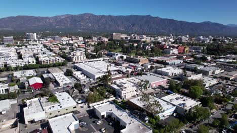 Pasadena-landscape-of-businesses,-aerial-rooftop-view-of-buildings-from-above,-mountains-on-a-clear-day