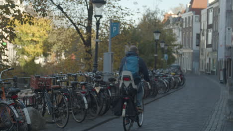 Radfahrer-Vorbei-An-Geparkten-Fahrrädern-Im-Alten-Stadtzentrum-In-Den-Niederlanden