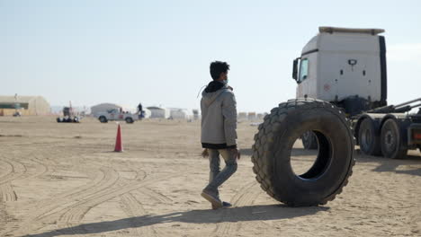 Local-Arabian-man-collecting-tires-at-the-Dakar-Rally,-left-to-right