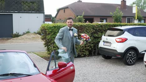 Groom-getting-out-of-the-car-with-flowers-to-see-his-wife-just-before-the-wedding