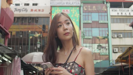 Asian-chinese-girl-looking-for-directions-in-Chinatown,-Kuala-Lumpur