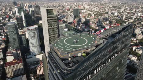 Aerial-spinning-shot-over-the-ritz-carlton-tower-in-mexico-city-with-spinning-movement-and-a-helipad-with-persons-on-there