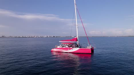 Aerial-zoom-in-of-people-celebrating-a-wedding-on-a-red-Catamaran-sailing-boat