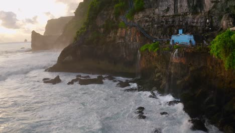 Stunning-aerial-shot-of-Nusa-Penida-Guyangan-Falls-during-sunset-and-golden-hour,-while-waves-are-crashing-on-the-cliffs