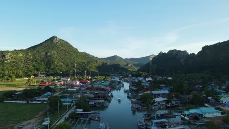 Aerial-footage-to-the-left-revealing-a-fishing-village,-boat-moving-in-the-middle