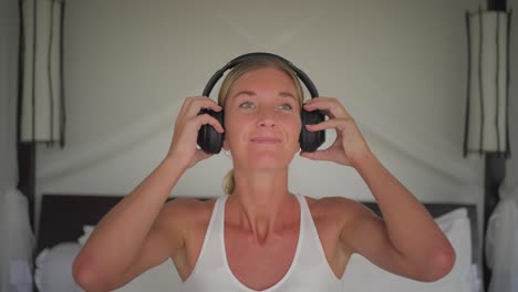 Blond-woman-puts-on-headphones,-listen-to-music-and-swaying-head,-carefree