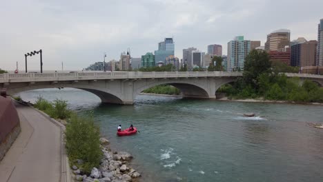 Couple-in-a-boat-in-City-river-bridge-skyline-pan-on-cloudy-day-Memorial-Drive-Monument-Calgary-Canada