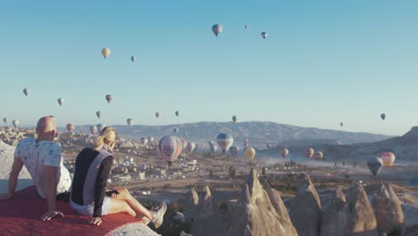 Couple-sitting-together-watching-the-hot-air-balloons-Cappadocia