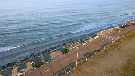 Aerial-hyper-lapse-along-coastline-road-showing-cars-movement-and-waves-reaching-the-shoreline