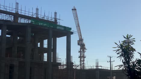 Crane-moving-behind-construction-building,-in-Piassa