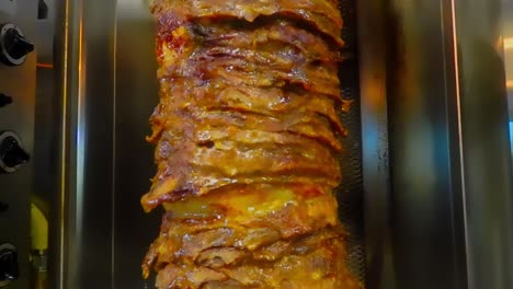 Endlosschleife-2-Von-5-Nahaufnahme-Von-Gestapelten-Steaks,-Die-In-Dünne-Scheiben-Geschnitten-Auf-Einem-Vertikalen-Grill-Mariniert-Und-Die-Säfte-Nach-Unten-Fließen,-Während-Das-Shawarma-Rindfleisch-Im-Arabischen-Stil-In-Einem-Edelstahlspieß-Langsam-Gegart-Wird