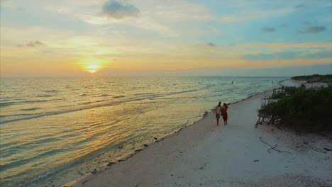 Young-attractive-couple-walks-on-a-beach-during-sunset