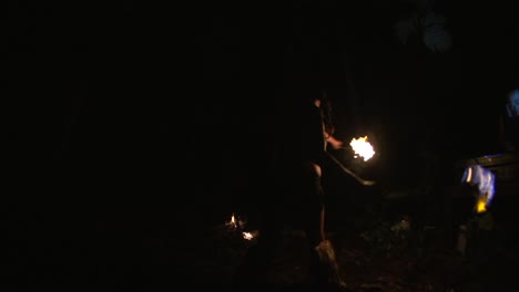 Wild-and-intense-fire-poi-dancing-performance-by-Asian-woman-during-night-time,-filmed-as-slow-motion-on-fish-eye-lens