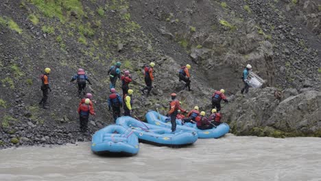 Group-of-people-getting-out-rubber-rafts-on-rocky-shore-of-powerful-mountain-river