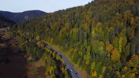Beautiful-aerial-view-of-a-mountain-road-surrounded-by-fall-foliage-forest-during-autumn-season