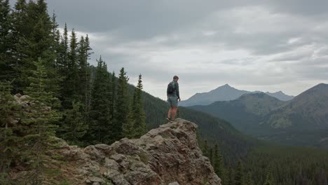 Hiker-stepping-on-ledge-circling-Rockies-Kananaskis-Alberta-Canada