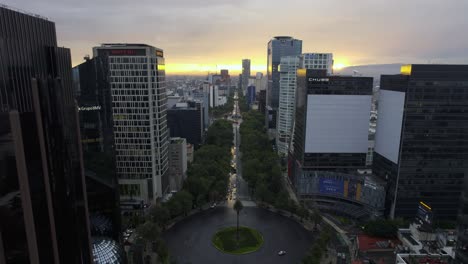 Aerial-view-overlooking-the-Reforma-Avenue,-dramatic-sunrise-in-Mexico-city---ascending,-drone-shot