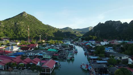 Reverse-aerial-footage-a-picturesque-fishing-village-revealing-house,-moored-fishing-boats,-a-boat-moving-out,-Bang-Pu-Fishing-Village,-Sam-Roi-Yot-National-Park,-Prachuap-Khiri-Khan,-Thailand