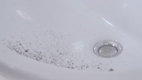 Slow-motion-view-of-shaved-beard-hair-falling-in-the-white-sink