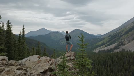 Hiker-standing-on-ledge-admiring-mountain-view-circled-Rockies-Kananaskis-Alberta-Canada