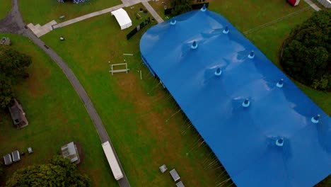 Pan-Up-Revealing-Aerial-Shot-Of-A-Empty-Music-Gig-blue-tent
