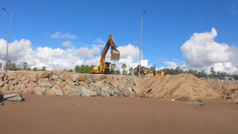 Bulldozer-creating-a-huge-wall-of-stones-near-a-beach-on-tropical-island-video-background-|-Bulldozer-machine-at-work-for-development-of-beach