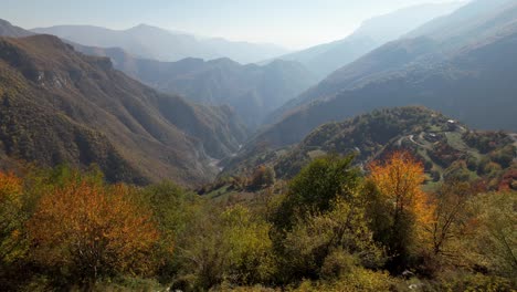 Paisaje-De-Pueblo-De-Montaña-Rural-En-Otoño-Con-árboles-Coloridos-Y-Fondo-De-Montañas-Nubladas-En-Los-Balcanes