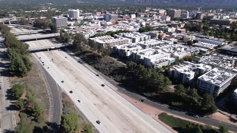 Aerial-view-flying-over-Pasadena-state-freeway-traffic-and-urban-Los-Angeles-business-skyline