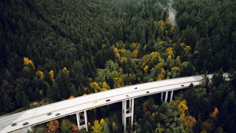 Cinematic-Aerial-Reveal-view-of-Cars-travelling-through-Mountain-Highway-Bridge-in-Fall,-North-Vancouver-BC
