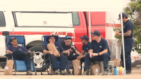 Firefighters-taking-a-break,-sitting-under-a-marquis-while-chatting-with-each-other