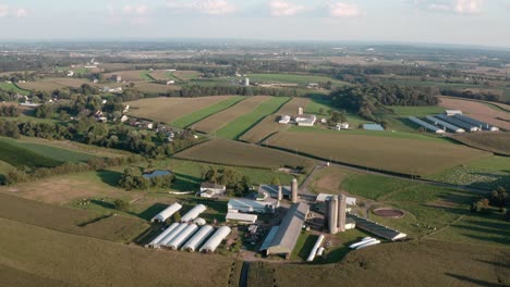 High-aerial-orbit-of-farm-buildings-and-greenhouse-barns,-silos