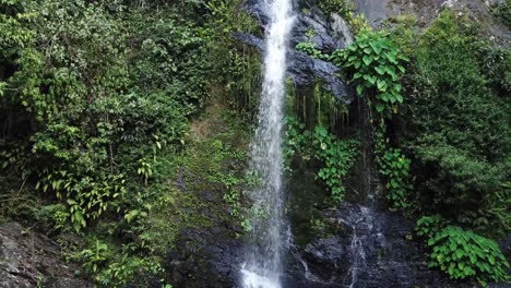 Drone-aerial-moving-towards-a-tropical-green-waterfall-in-rainforest