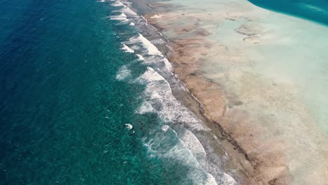 Aerial-view-tilt-up-waves-crash-on-sebastopol-barrier-reef,-foam-and-splash