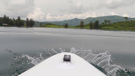 Low-POV-paddleboard-view-of-green-jungle-Lake-Kivu-with-small-waves