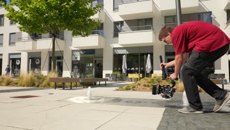 Young-Man-With-Gimbal-and-Camera-Shooting-Low-Angle-Video-Scene-in-City-Exterior-50fps