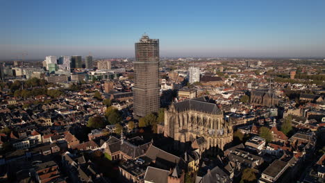 Closing-in-on-De-Dom-medieval-cathedral-tower-in-scaffolding-in-Dutch-city-center-of-Utrecht-towering-over-the-urban-cityscape-with-architectural-details-of-the-remaining-body-of-the-church