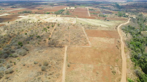 Luftaufnahme-Einer-Trockenen-Landschaft-Mit-Einem-Kleinen-Streifen-Grüner-Bäume-Im-Ländlichen-Kenia