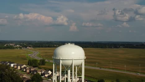 Water-Tower-With-Vehicles-Driving-Through-Fields-On-A-Sunny-Day