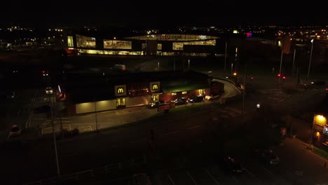 McDonalds-fast-food-drive-through-flying-at-night-over-Northern-UK-city-aerial-view