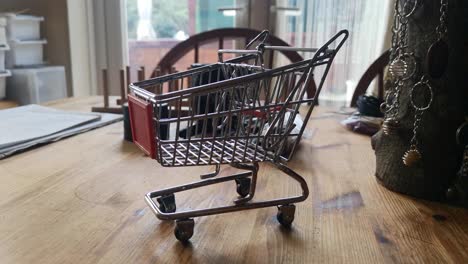 Small-shopping-trolley-online-home-business-concept-on-kitchen-table-copy-space-closeup-dolly-left
