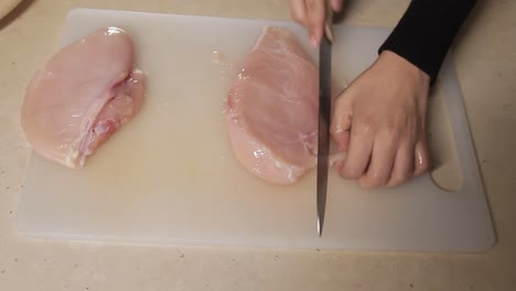 top-view-of-chef-cutting-chicken-meat-on-kitchen-table