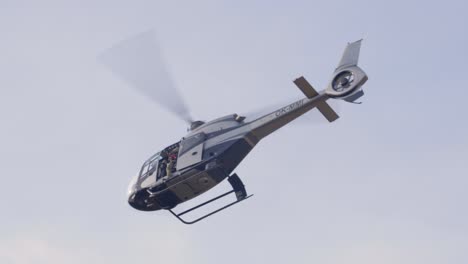 Police-Helicopter-With-Officer-Holding-Sniper-Flying-in-the-Sky,-Low-Angle-View
